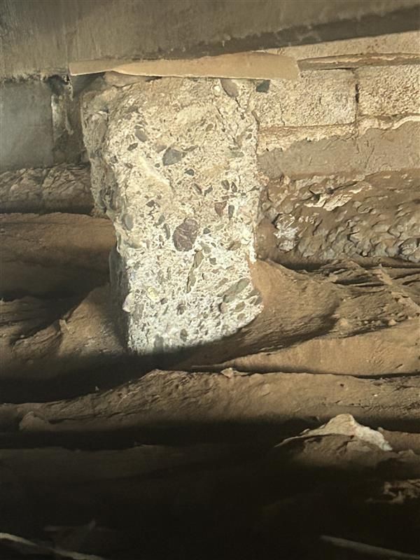 Rough stone pillar supporting a low stone wall in a dim cave or cellar Rough stone pillar supporting a low stone wall in a dim cave or cellar