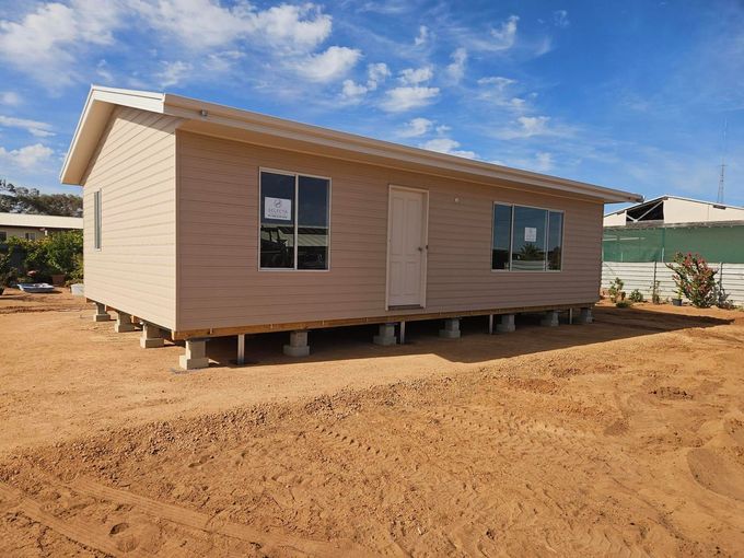 Small beige house on stilts in a sandy construction area under a blue sky Small beige house on stilts in a sandy construction area under a blue sky