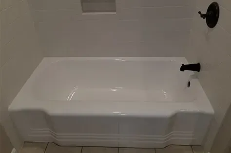 White bathtub with black faucet and showerhead in a tiled bathroom.