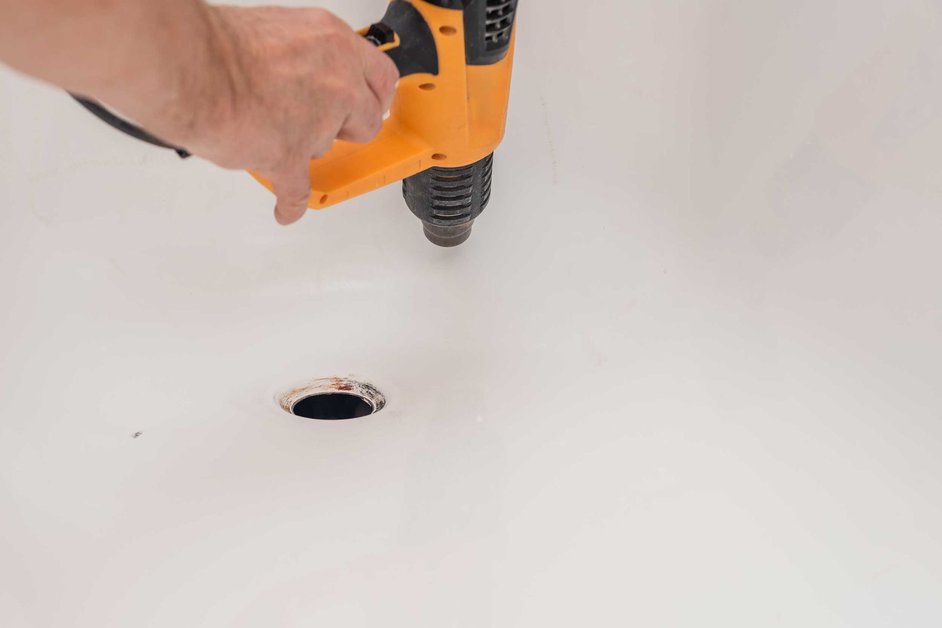 Closeup photo of a man with an electric heat gun drying the bath surface.