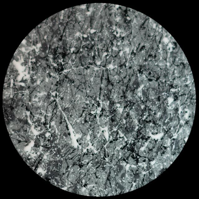 Close-up of a circular dark gray and white textured surface, possibly stone, with cracks.