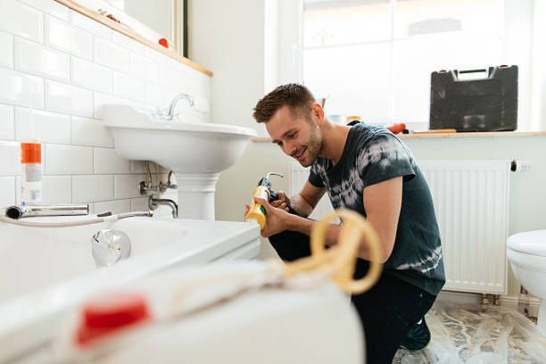 Man using silicone in a bathtub repair.