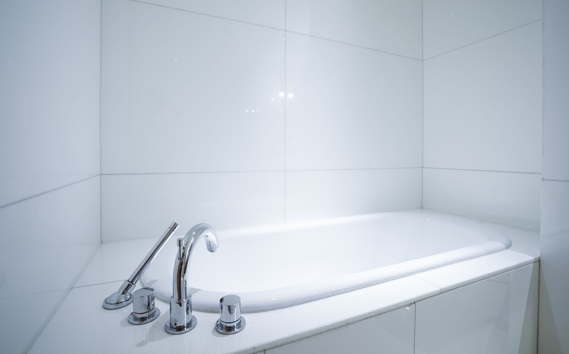Modern white bathtub with chrome fixtures in a tiled bathroom. Modern white bathtub with chrome fixtures in a tiled bathroom.