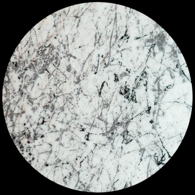White circle with gray and black splatters and streaks.
