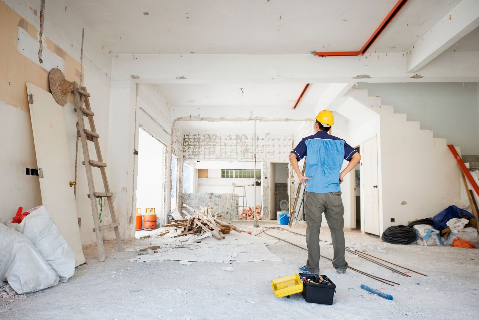 A man in a hard hat is standing in a room under construction.