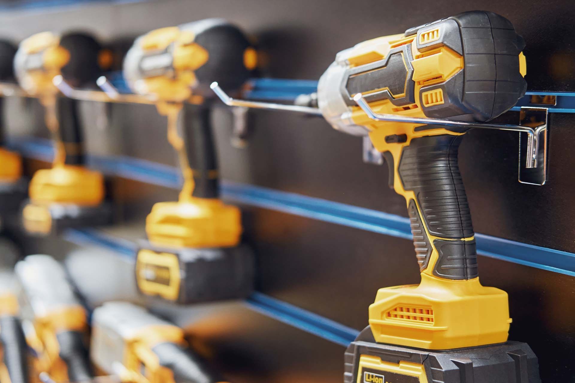 Yellow and black cordless power drills on display racks in a store.