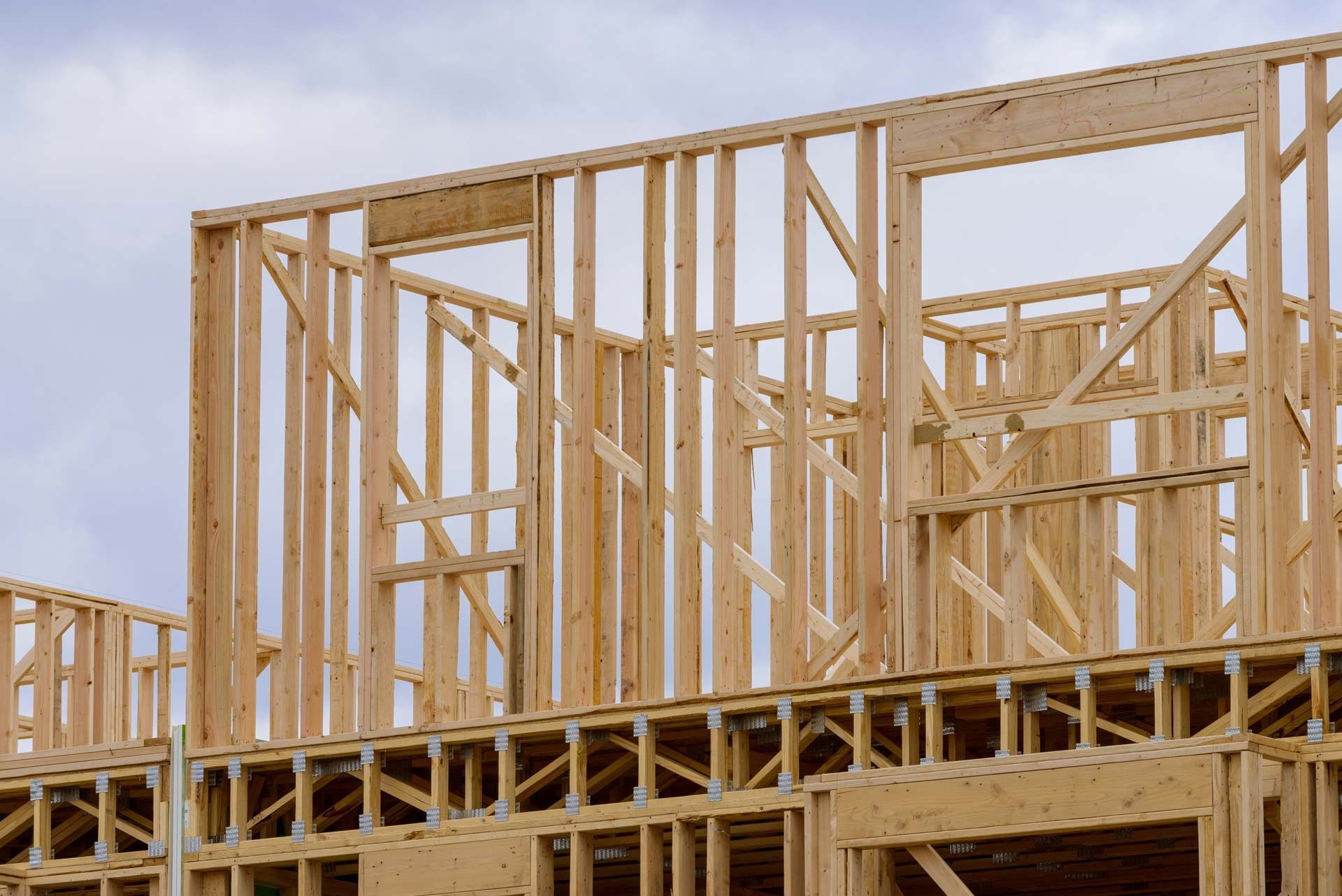 The wooden framing of a building under construction against a cloudy sky.