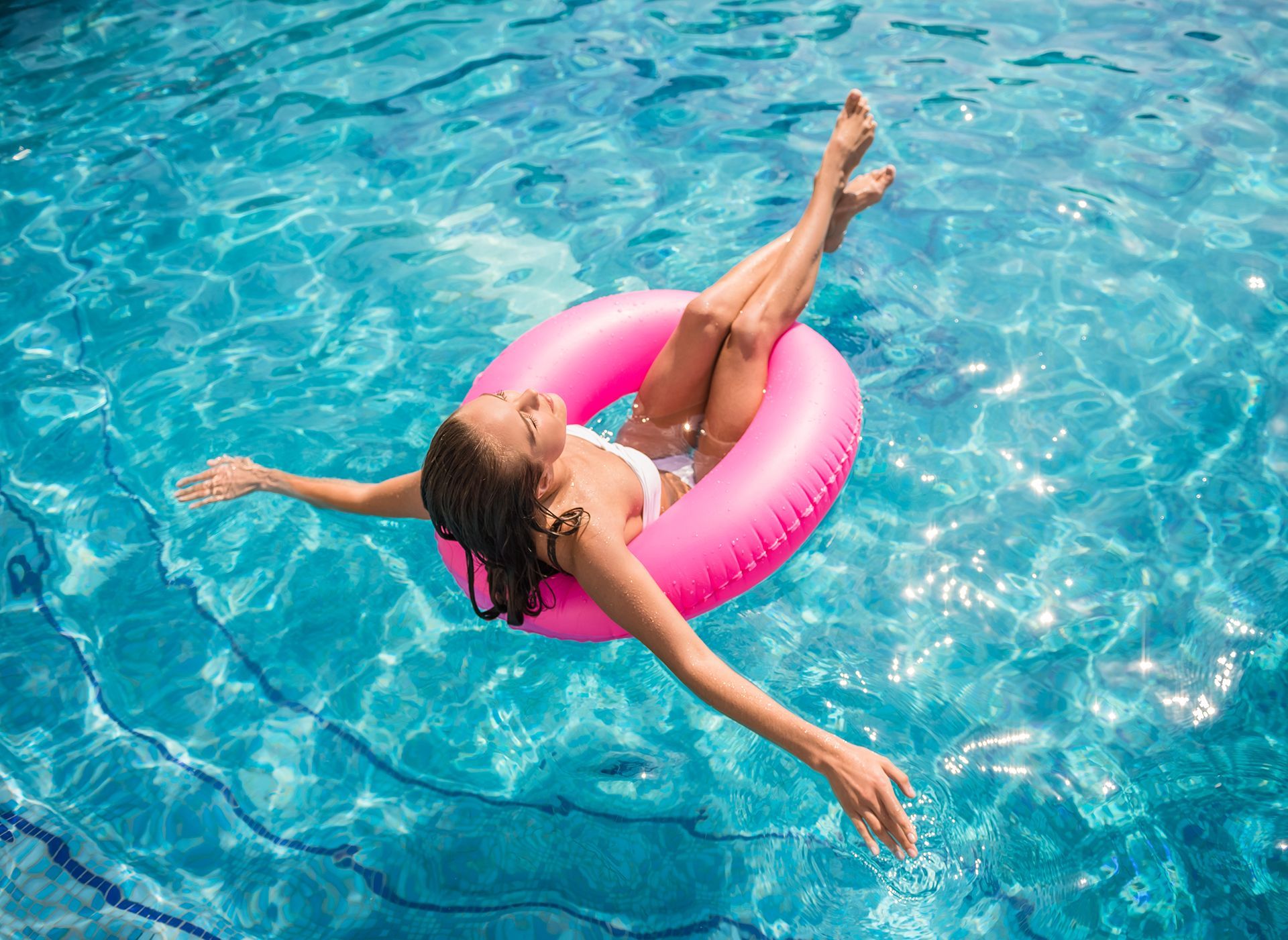 Woman Floating on a Pink Inflatable Ring in a Swimming Pool