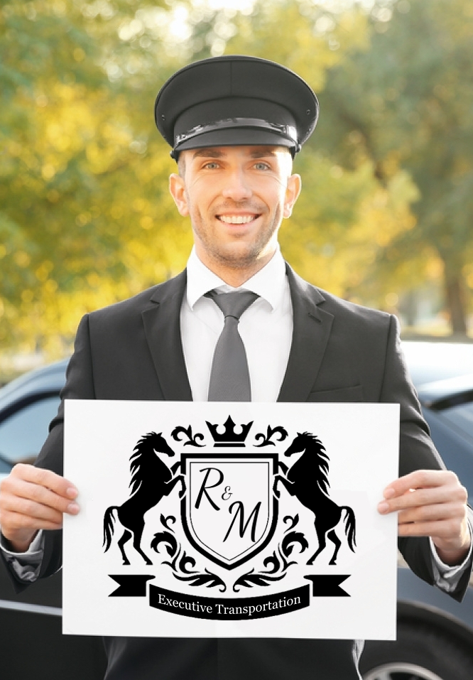 A man in a suit and tie is holding a sign in front of a car.