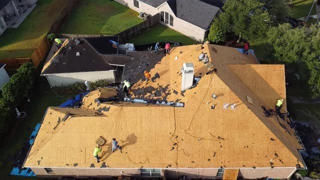 Aerial view of a crew installing new plywood roof decking on a residential home.