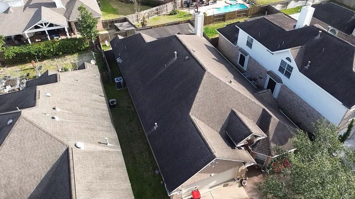 An aerial view of a residential neighborhood showing rooftops, houses, and a narrow lawn between two properties.
