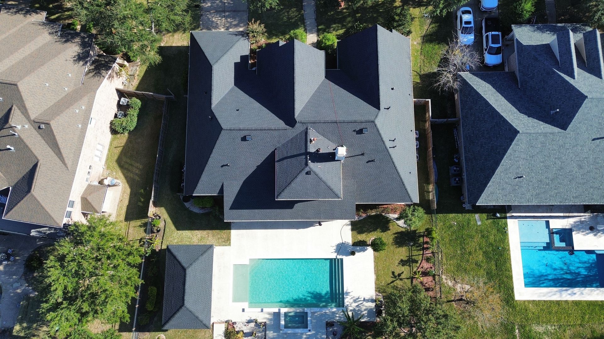 Aerial view of a residential manufactured home with a gray shingle roof, tan siding, and a white back door.