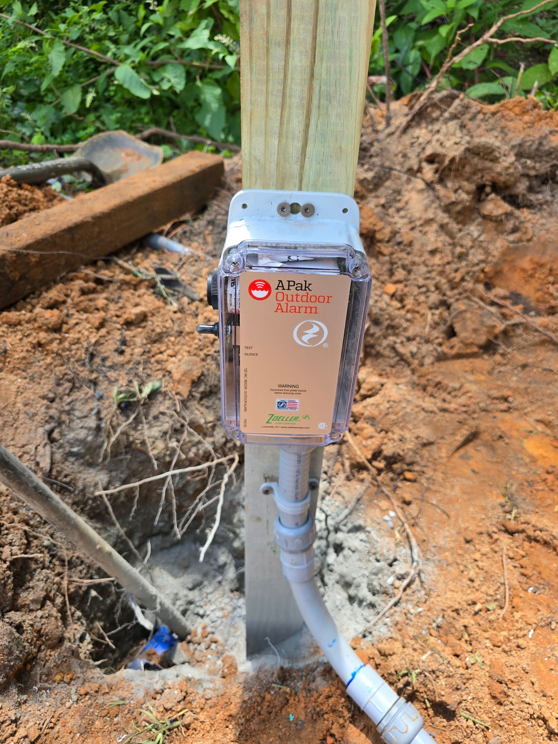 An AT&T cellular device enclosure is mounted on a wooden post in an outdoor setting.