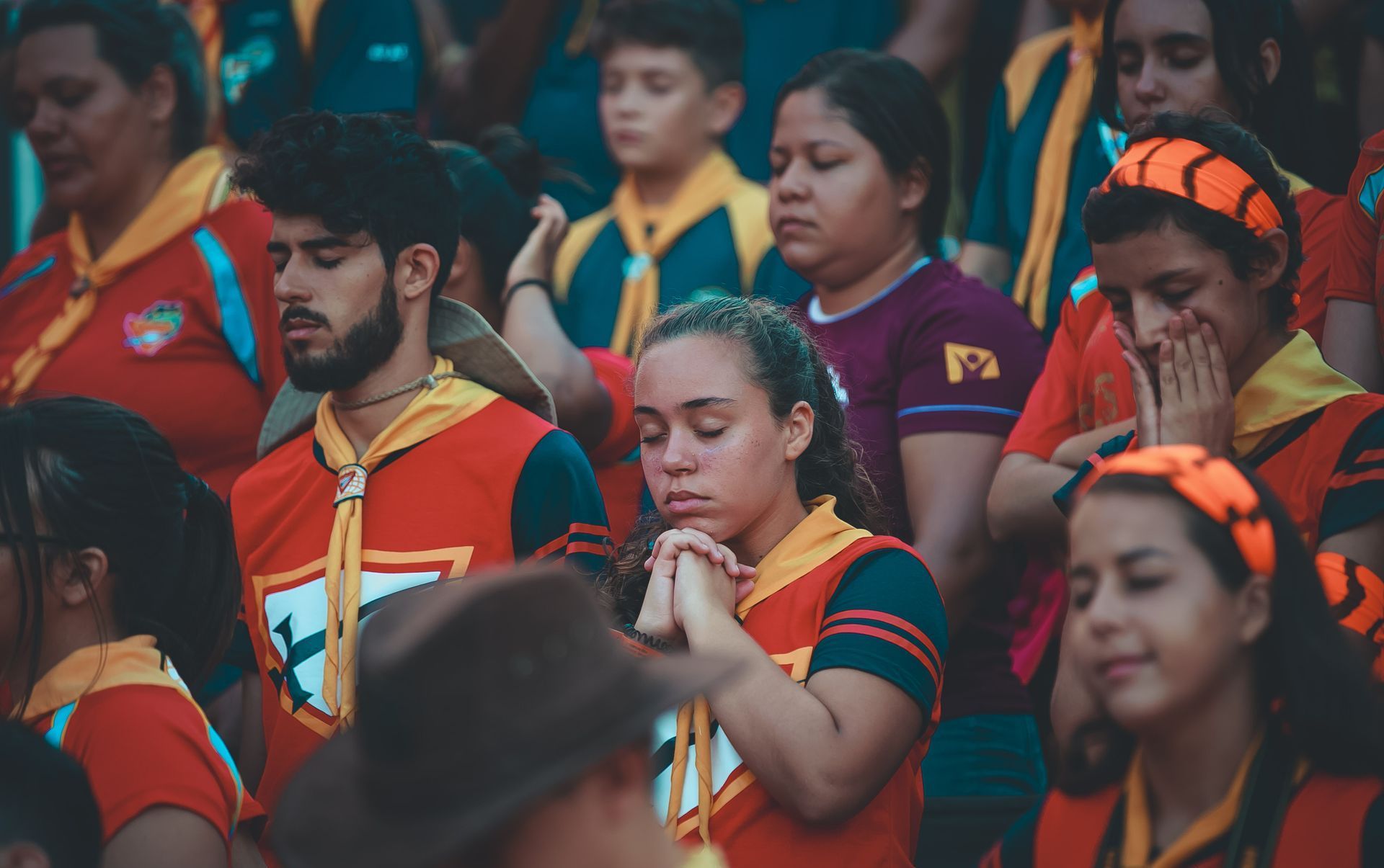 A group of people are sitting in a stadium with their eyes closed.