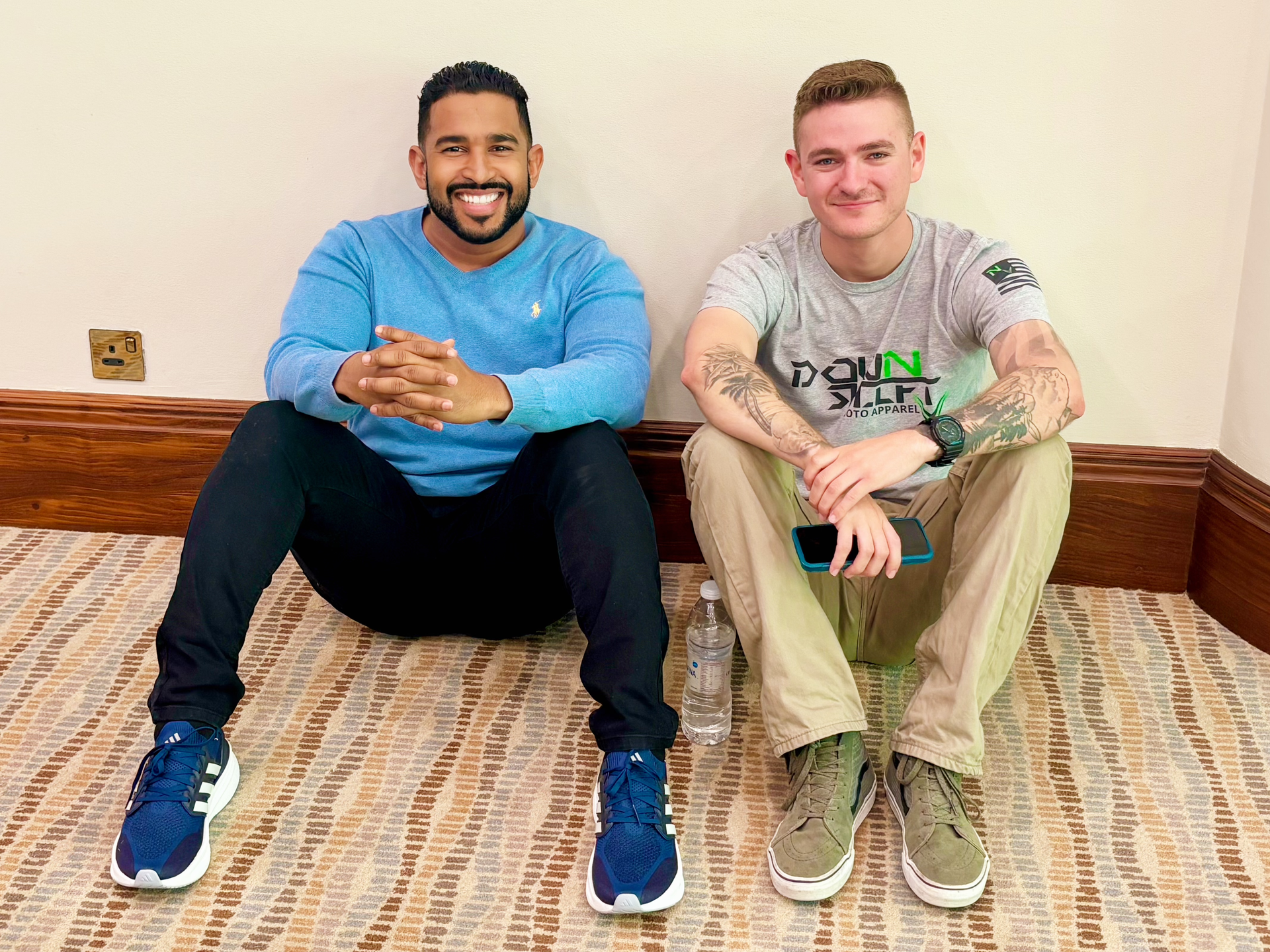 Two men are sitting on the floor next to each other.