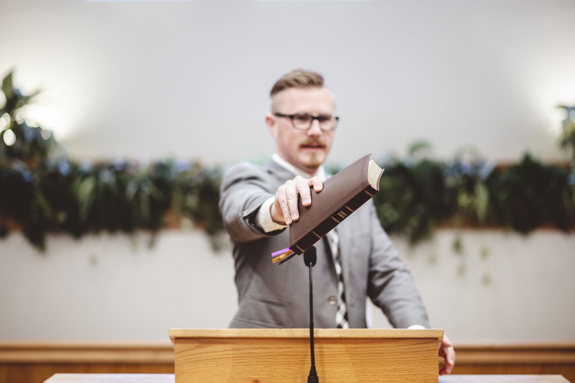 A man is standing at a podium holding a bible.