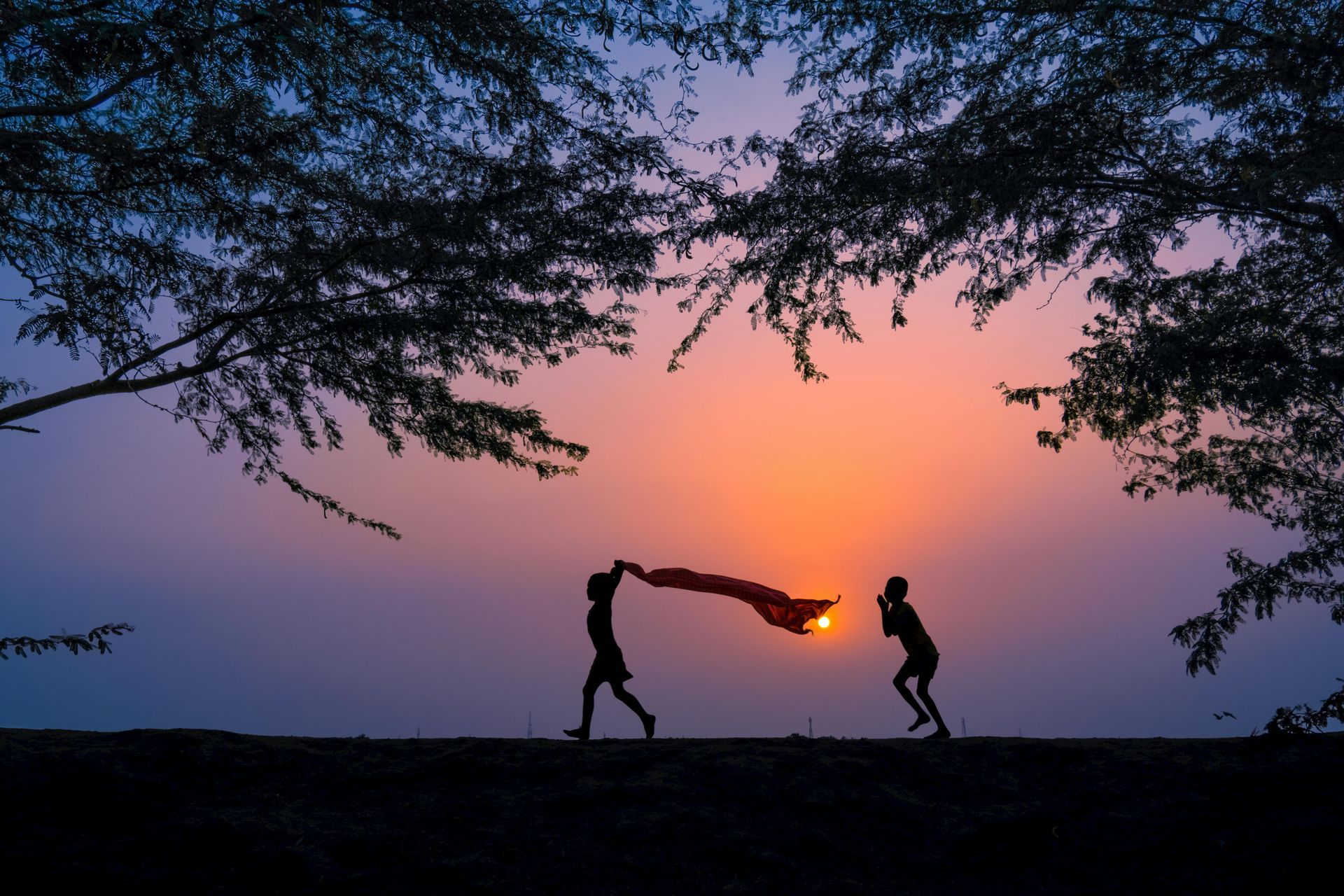 Two people are playing with a kite at sunset.