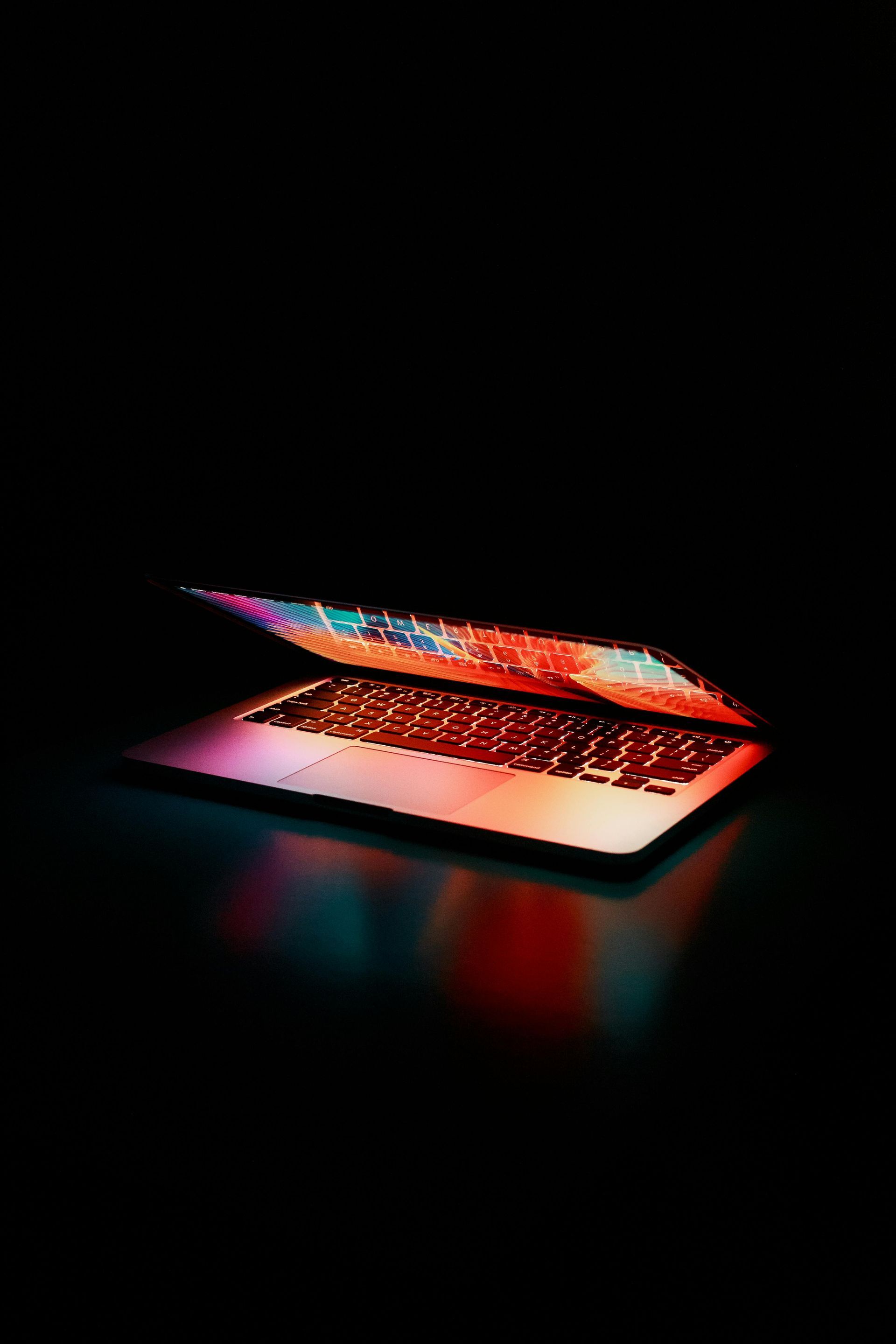 A laptop computer is open and sitting on a table in the dark.