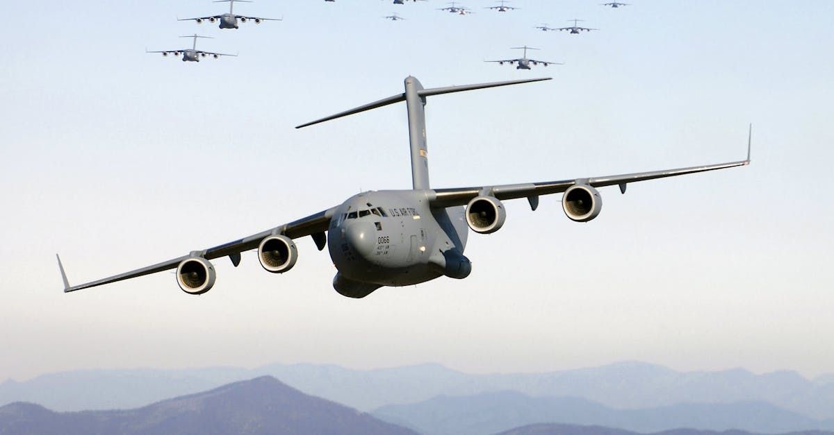 A large military plane is flying through a cloudy sky.