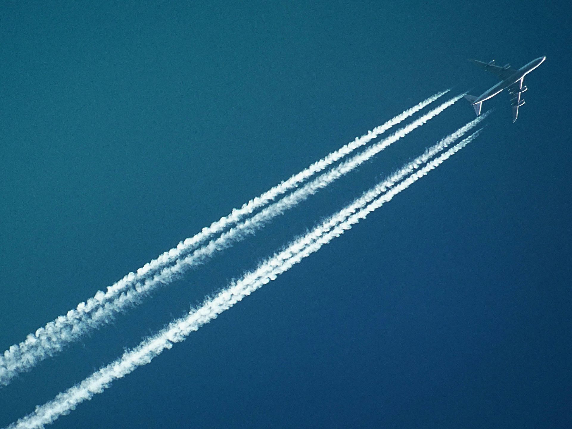 A plane is flying through a blue sky with smoke trails