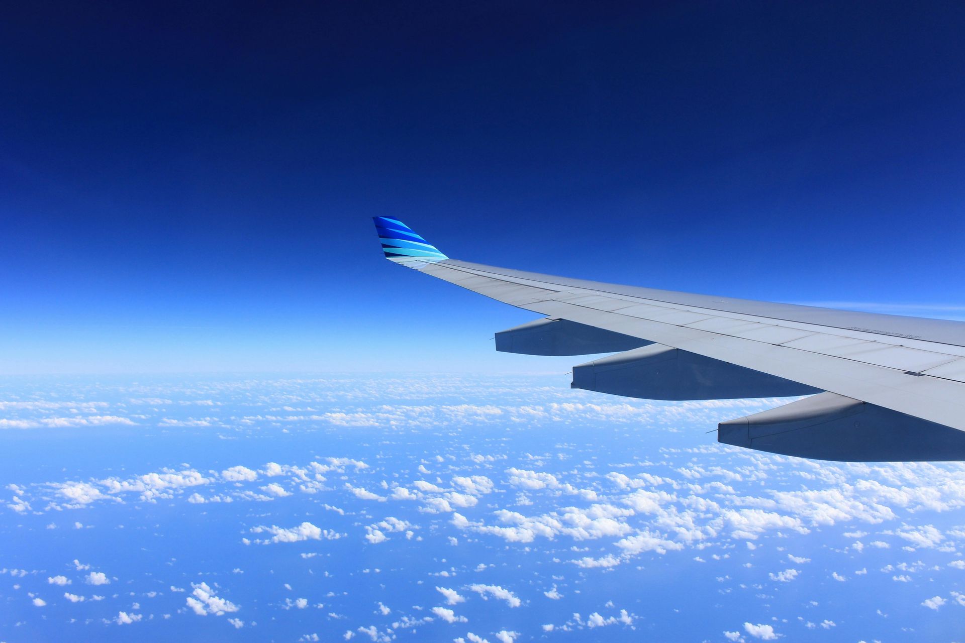 The wing of an airplane is visible in the sky above the clouds