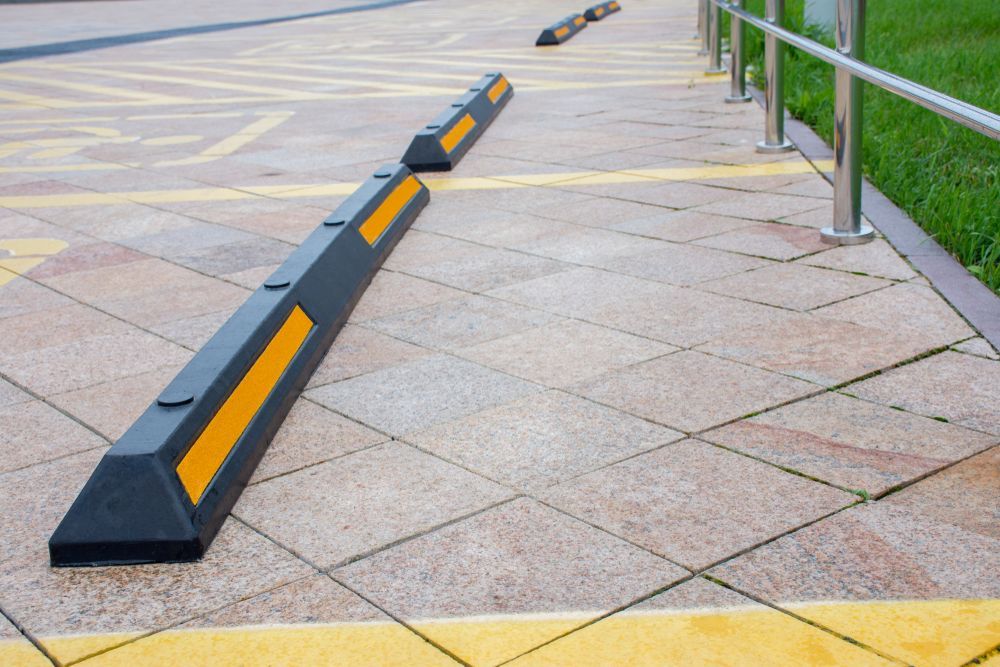 A Row of Black and Yellow Parking Blocks on a Sidewalk — North Coast Line Marking in Talofa, NSW