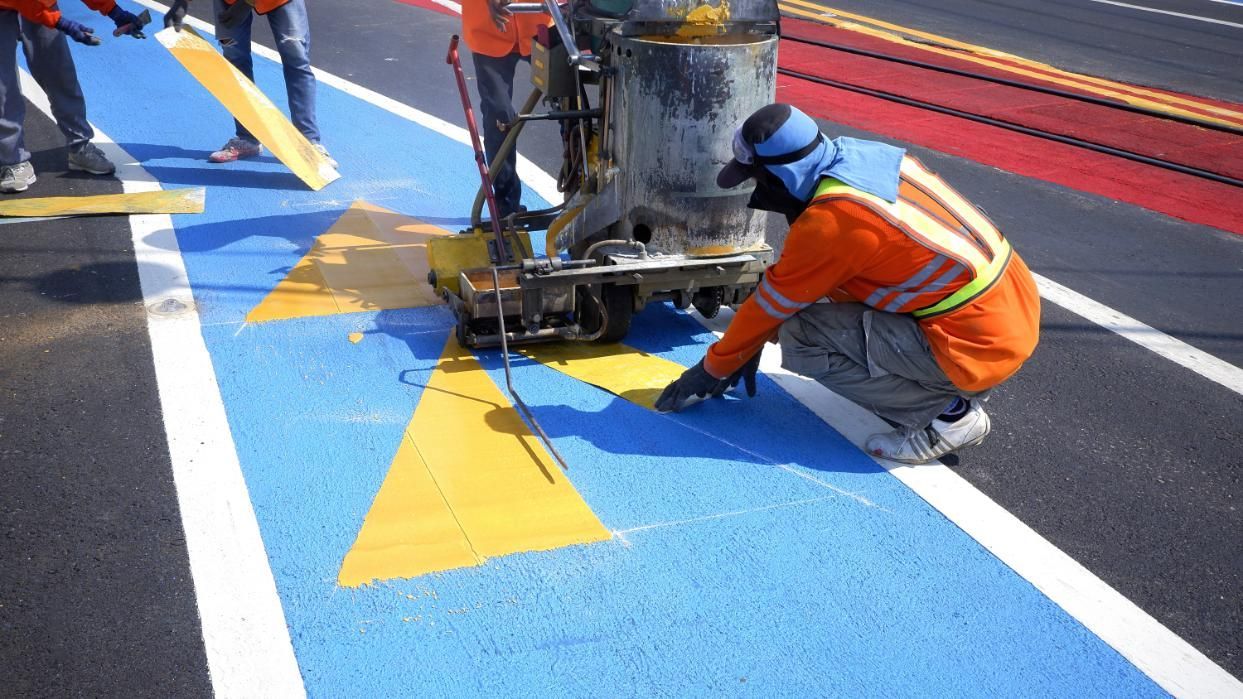 A Man is Kneeling Down While Painting a Road With a Machine — North Coast Line Marking in Talofa, NSW