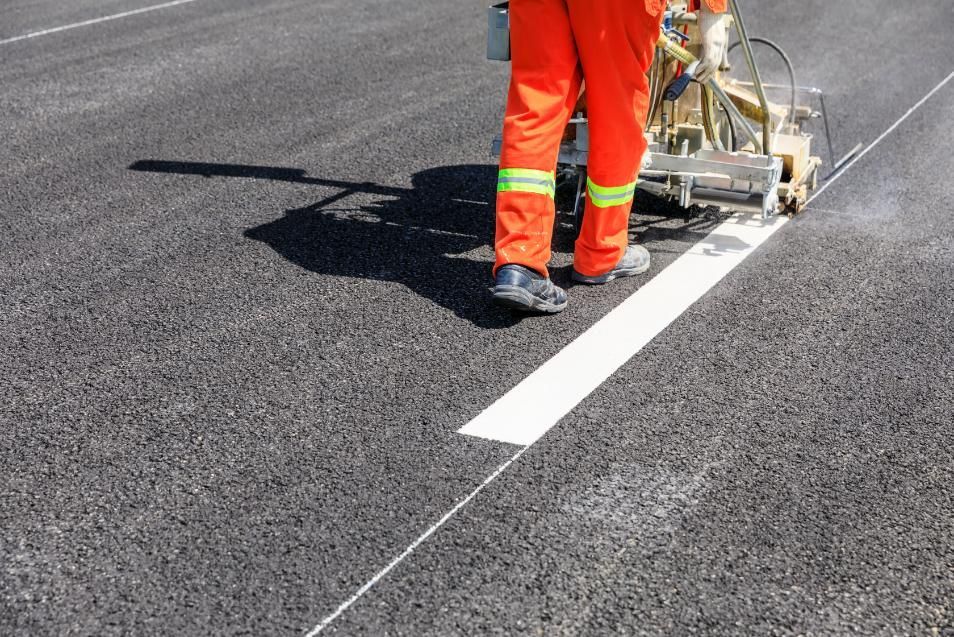 A Man in Orange Pants is Painting a White Line on the Road — North Coast Line Marking in Coffs Harbour, NSW