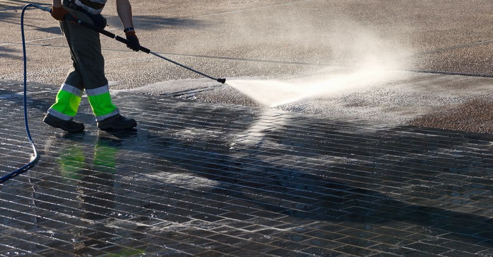A Man is Using a High Pressure Washer to Clean a Concrete Surface — North Coast Line Marking in Talofa, NSW