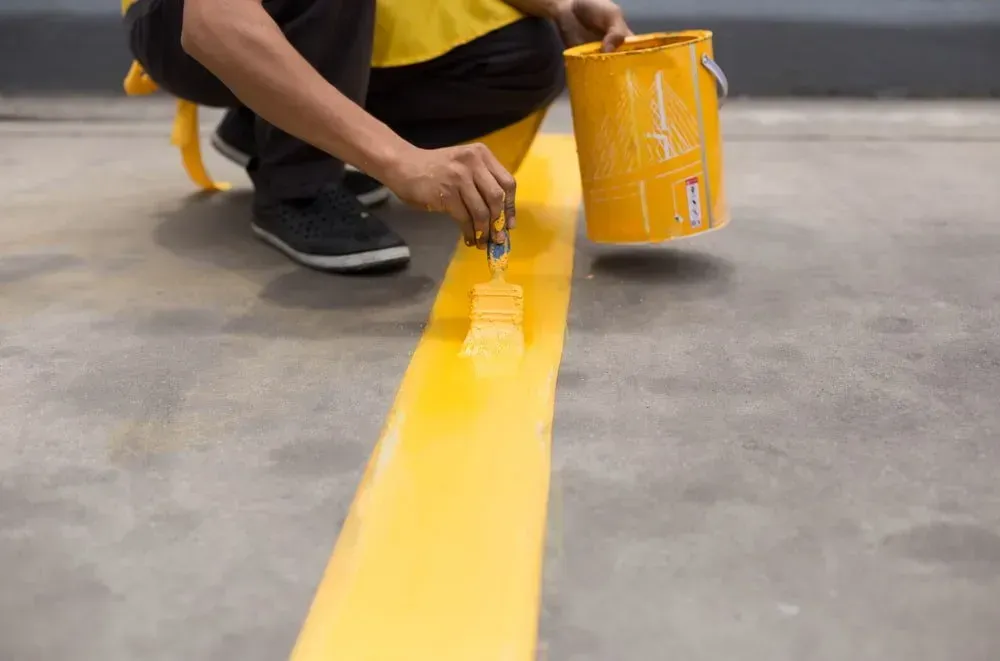 A Man is Kneeling Down and Painting a Yellow Line on the Ground — North Coast Line Marking in Coffs Harbour, NSW