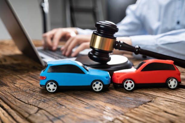 Judge gavel with toy cars and laptop, symbolizing car accident legal case online.