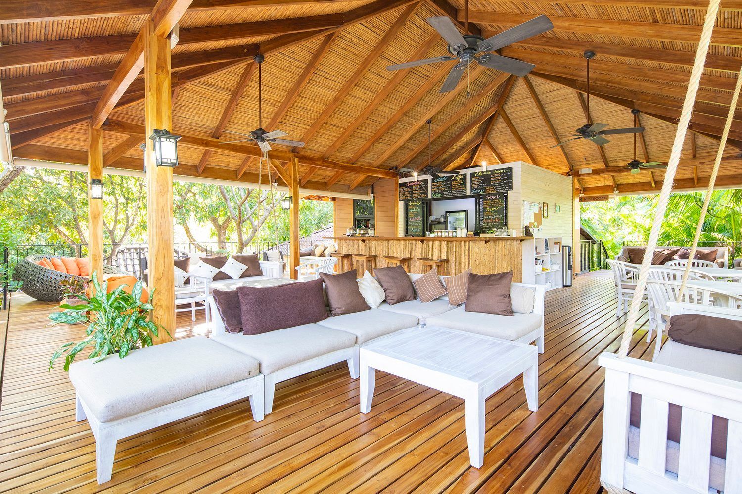 A wooden deck with a couch , table , and ceiling fan.