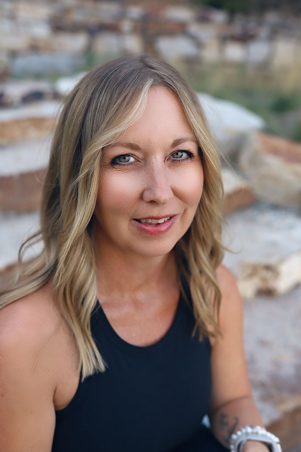 The woman is wearing a black tank top and smiling for the camera.
