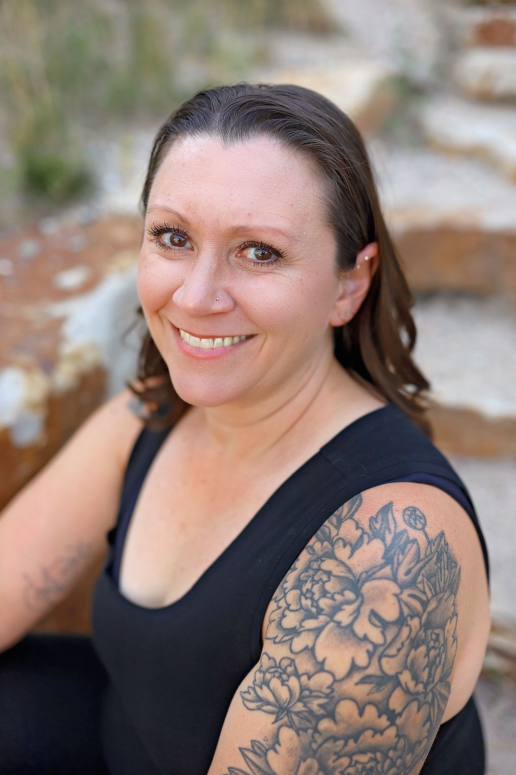 A woman with a tattoo on her arm is smiling for the camera.