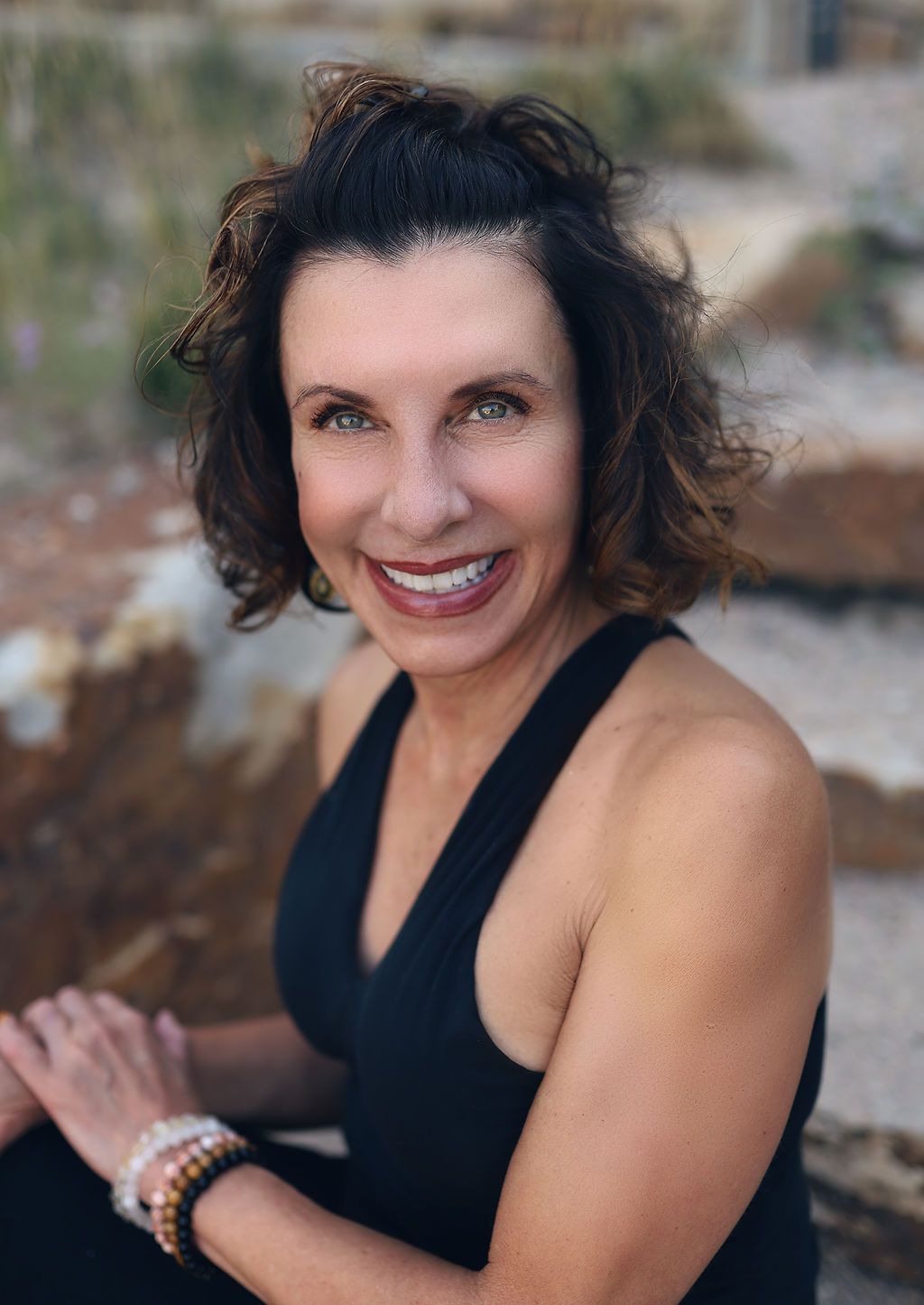 A woman in a black tank top is smiling for the camera.