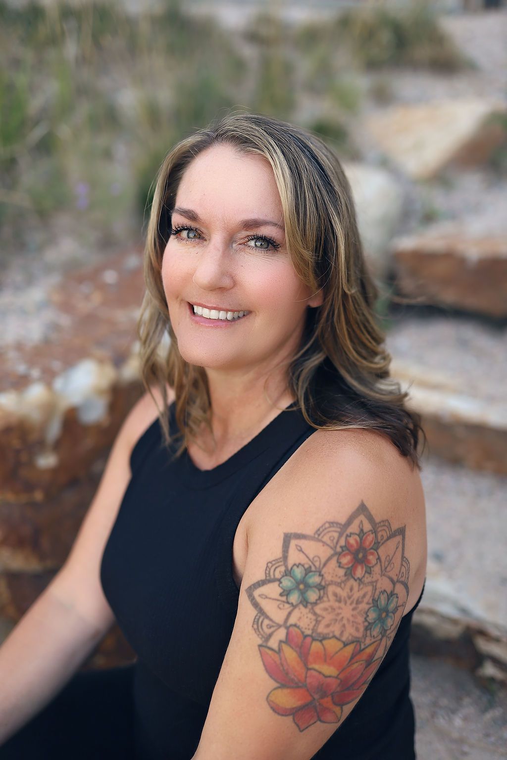 A woman with a tattoo on her arm is smiling for the camera.