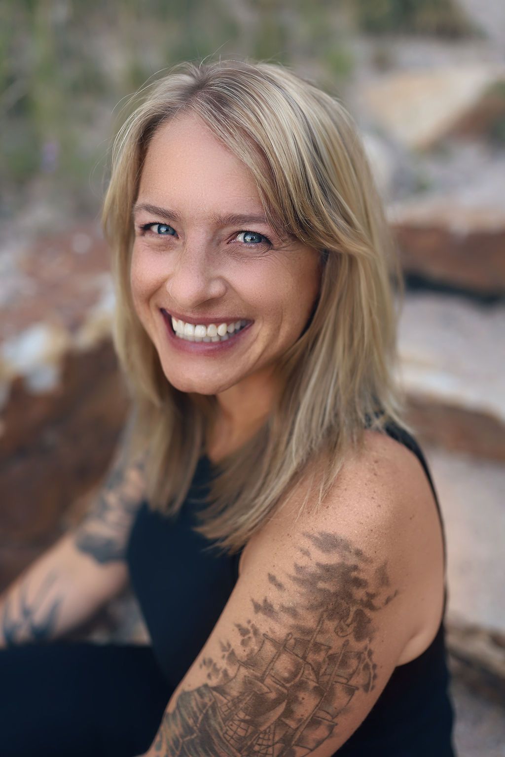 A woman with tattoos on her arm is smiling for the camera.