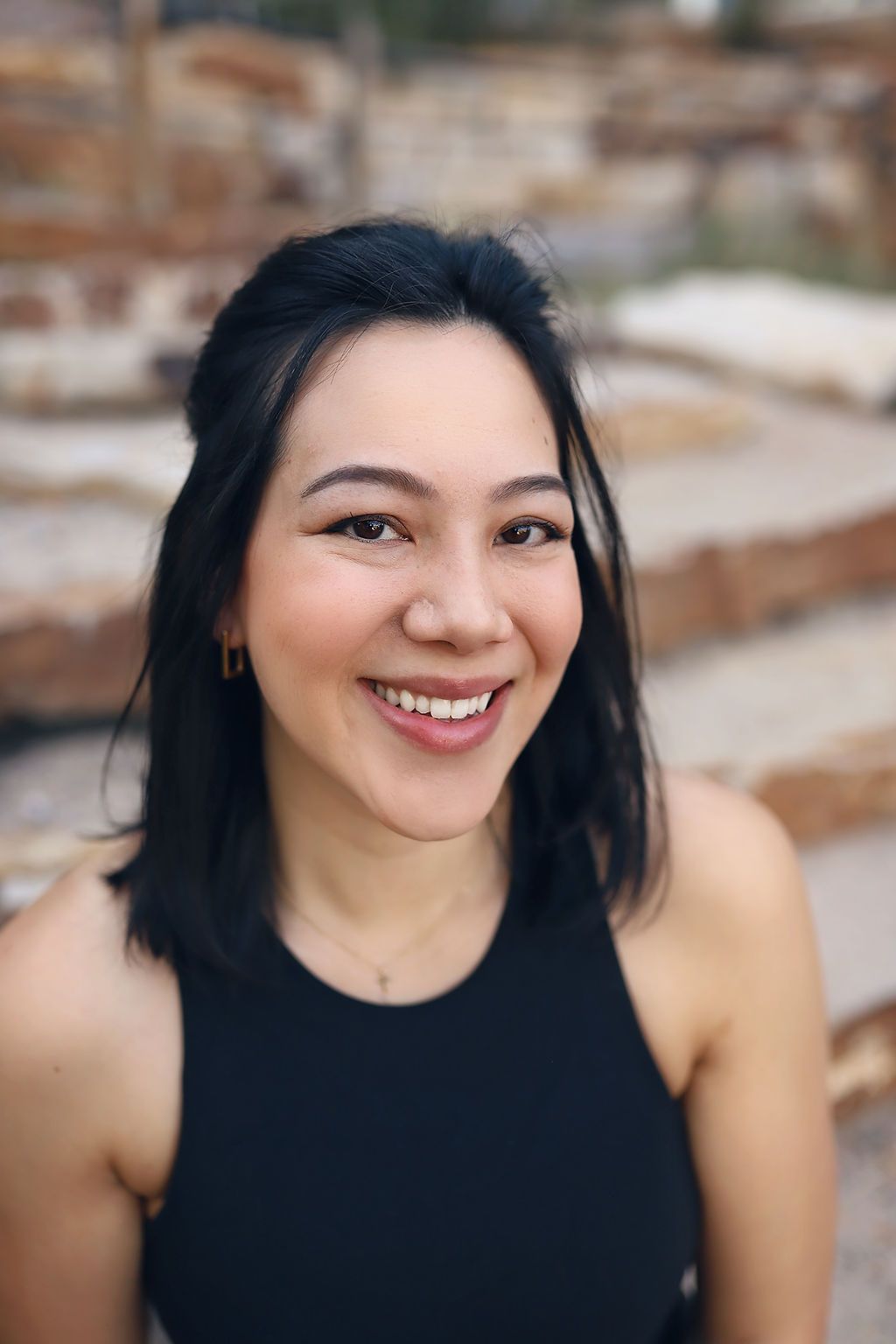 A woman in a black tank top is smiling for the camera.