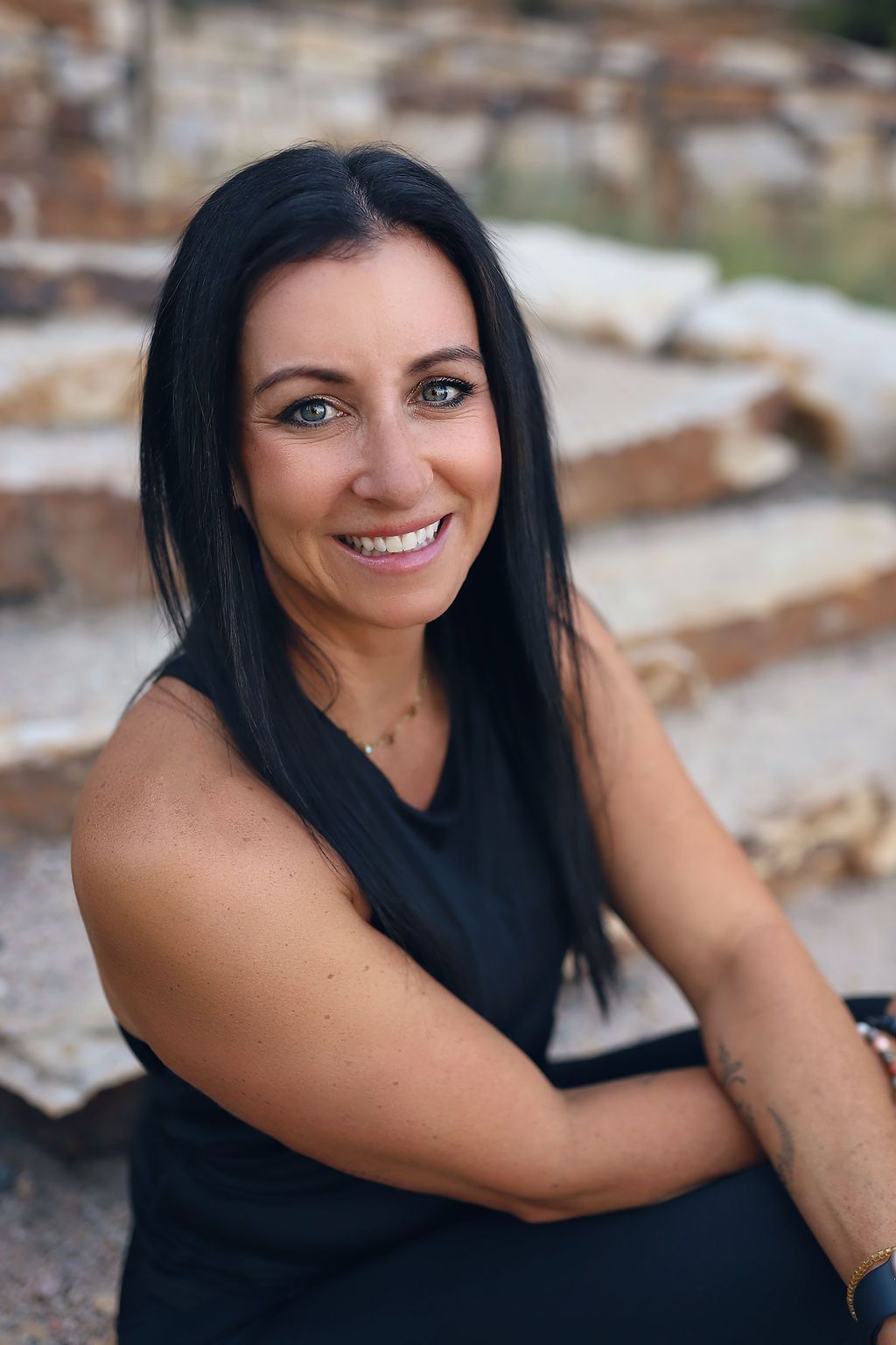 A woman is sitting on a set of stairs and smiling for the camera.