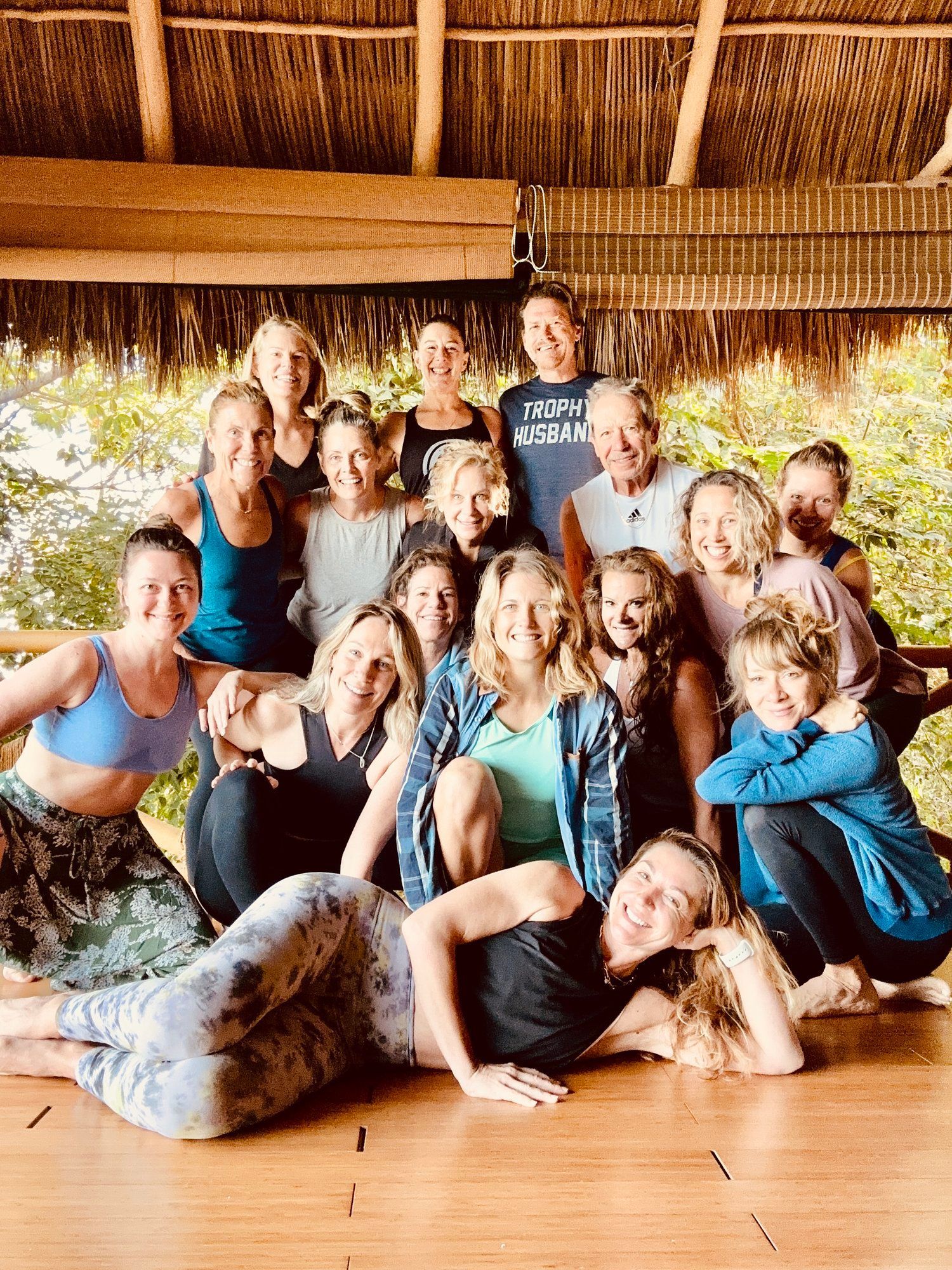 A group of people are posing for a picture in a room with a thatched roof.