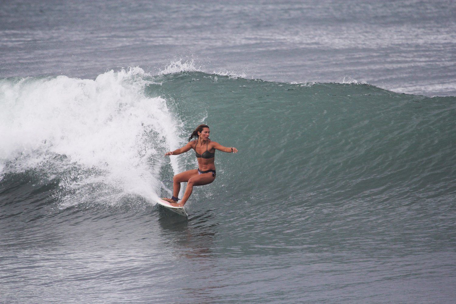 A woman is riding a wave on a surfboard in the ocean.