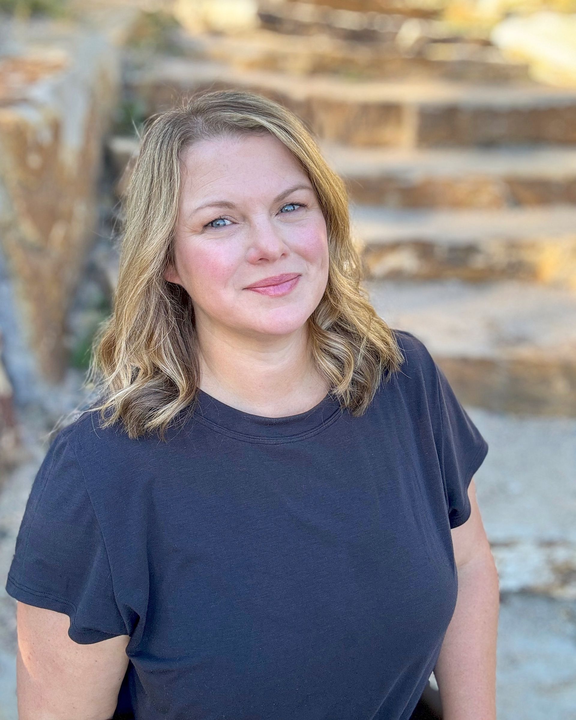 A woman in a black shirt is standing in front of a set of stairs.