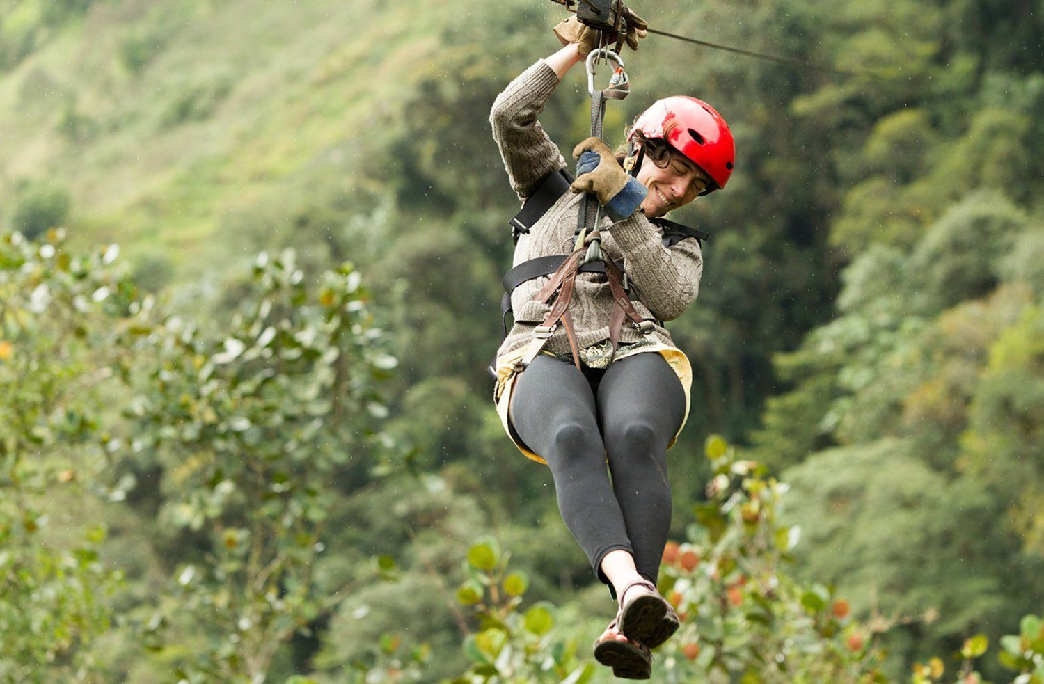 A woman is flying through the air on a zip line.