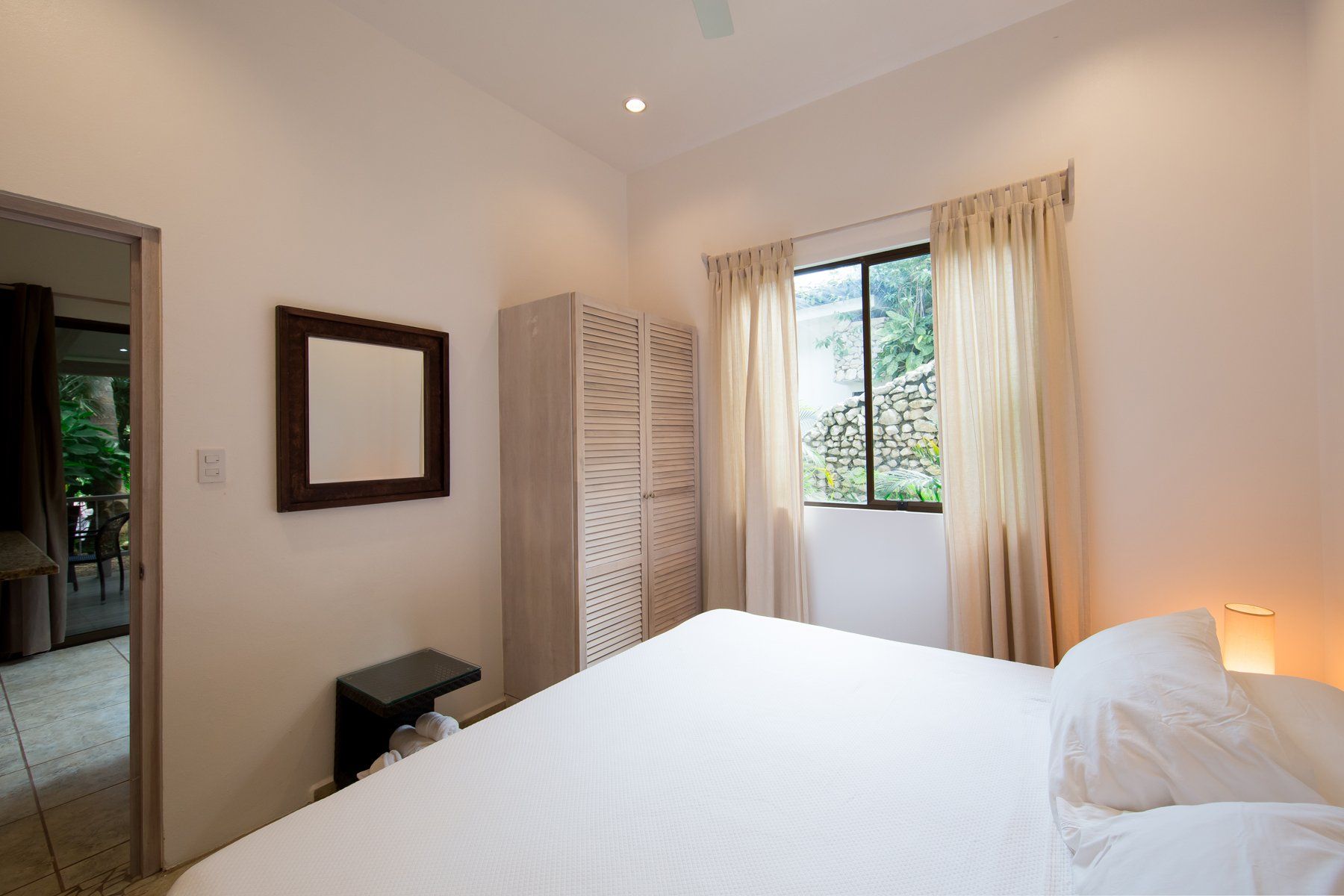 A bedroom with a large bed , a mirror and a window.