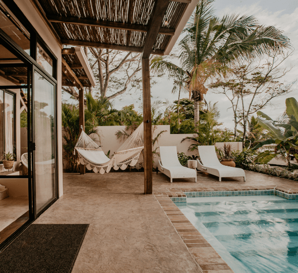 A patio with a hammock and lounge chairs next to a swimming pool