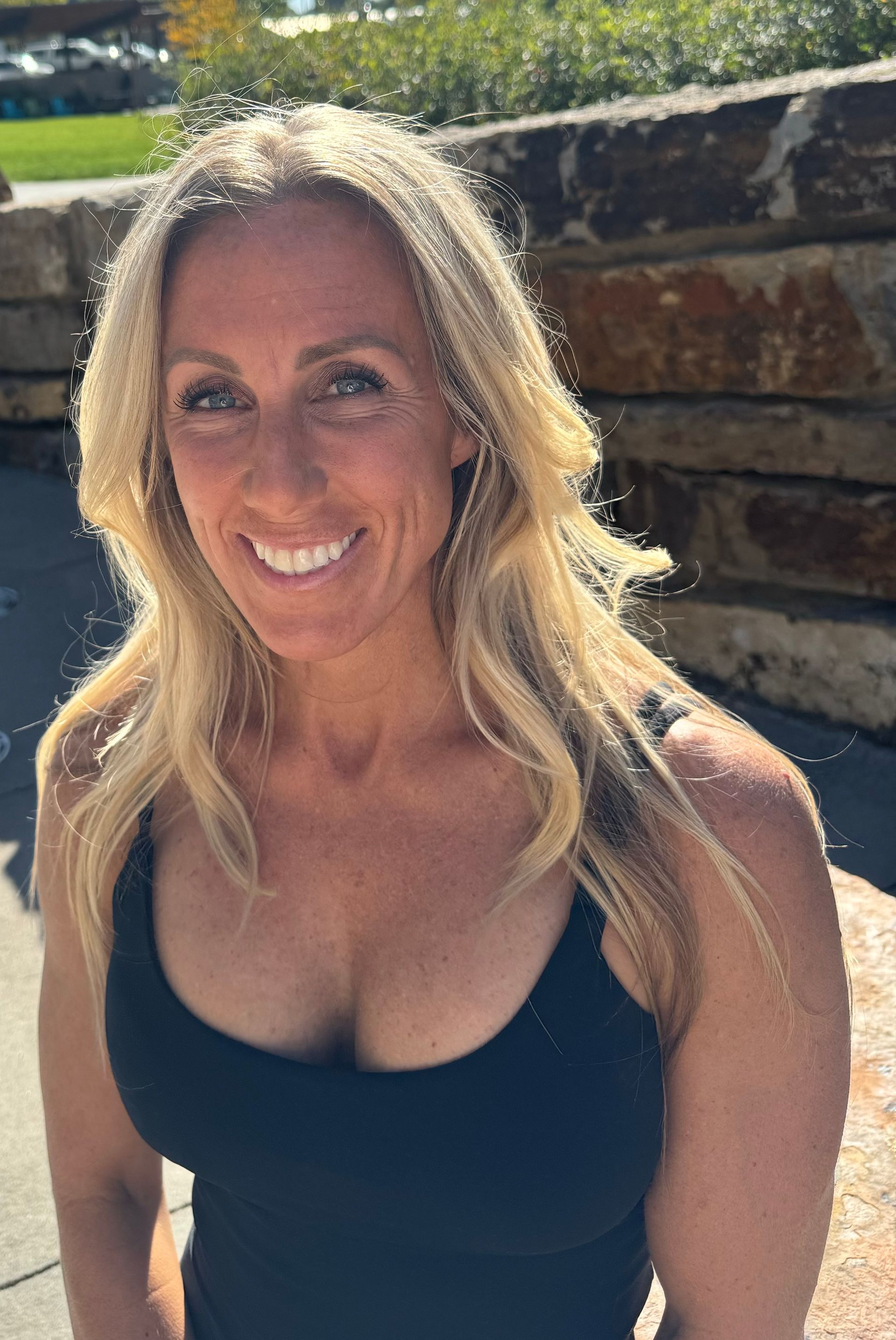 A woman in a black tank top is smiling for the camera.