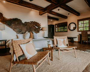 A bedroom with a bed , chairs , a table and a mirror.
