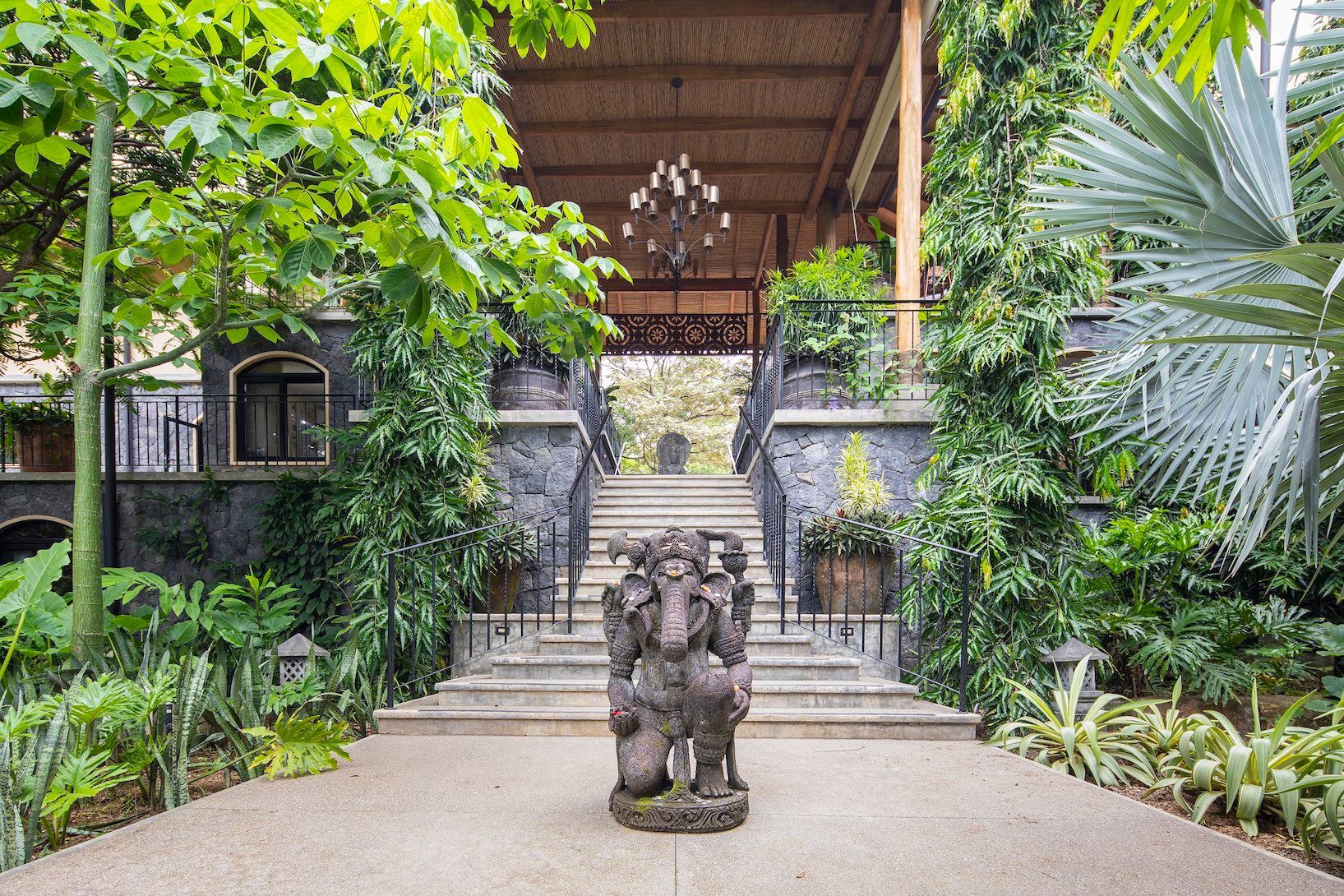 A statue of a deity is sitting in the middle of a lush green garden.