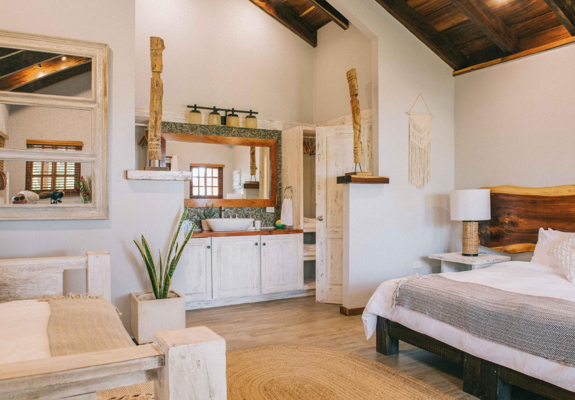 A bedroom with a bed , chair , sink and mirror.