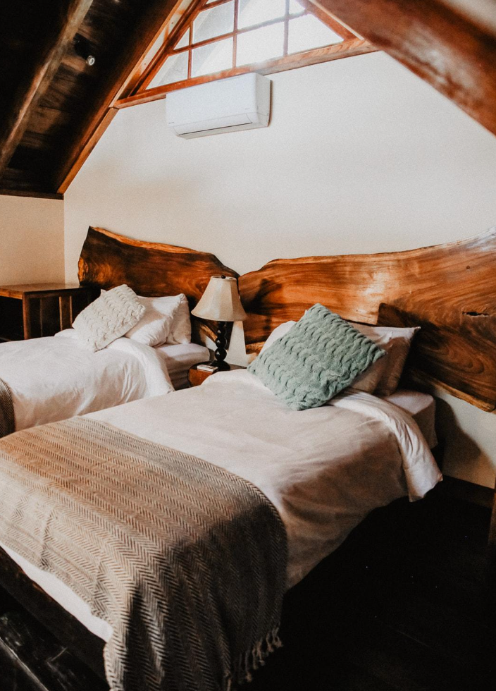 A bedroom with two beds and a wooden headboard